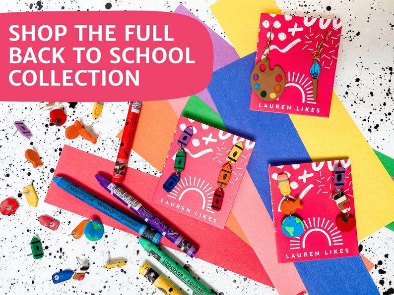 May include: Three cards with colorful back to school themed earrings. Each card has the text "LAUREN LIKES" and features a different set of earrings. The earrings are made of polymer clay and feature school supplies like crayons, paintbrushes, and a globe.