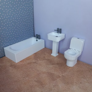 May include: A white bathroom set with a bathtub, toilet, and pedestal sink. The bathroom is decorated with light blue wallpaper with white polka dots.