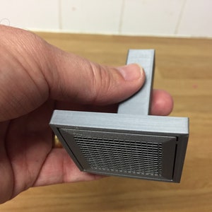 May include: A grey 3D printed vent cover with a square shape and a black metal mesh grille.