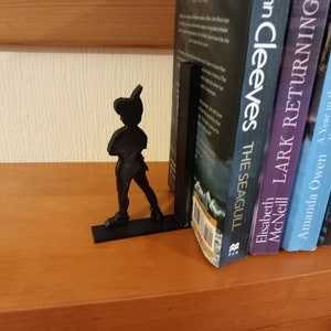 May include: Black bookends shaped like Peter Pan, holding up a row of five books. The books are titled "The Seagull", "Lark Returning", "A Year in the Life of the Yorkshire Shepherdess", "Wishes of the Sea", and "Christmas with the Inghams".