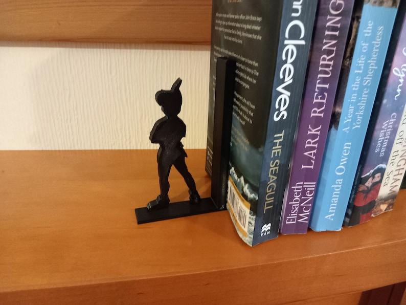 May include: Black bookends shaped like Peter Pan, holding up a row of five books. The books are titled "The Seagull", "Lark Returning", "A Year in the Life of the Yorkshire Shepherdess", "Wishes of the Sea", and "Christmas with the Inghams".