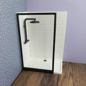 May include: A white tiled shower cubicle with a black frame and a black shower head. The shower cubicle is in a corner of a room with a wooden floor.