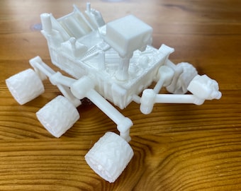 May include: A white 3D printed model of a Mars rover with six wheels and a robotic arm.