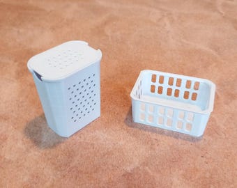 May include: Two white plastic storage baskets with a grid pattern. The larger basket has a lid.