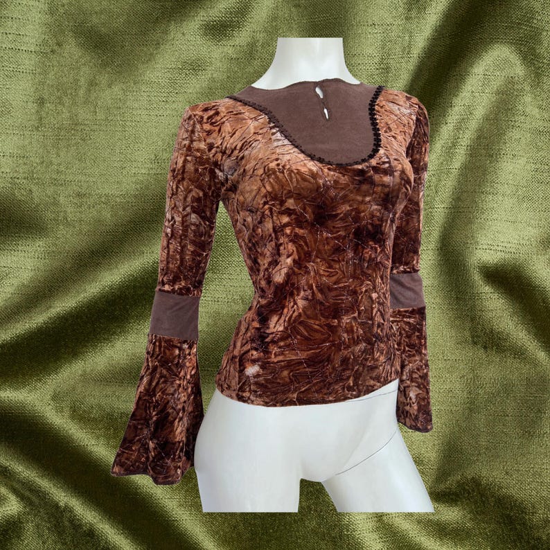 May include: A brown velvet top with a bell sleeve and a brown lace trim around the neckline. The top has a crinkled texture.