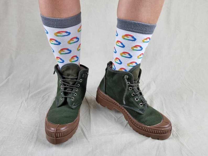 May include: A pair of dark green canvas boots with brown rubber soles and laces. The boots are worn with white socks featuring a repeating pattern of colorful cloud-shaped logos.