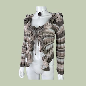 May include: A brown and white striped knit cardigan with a ruffled front and long sleeves.