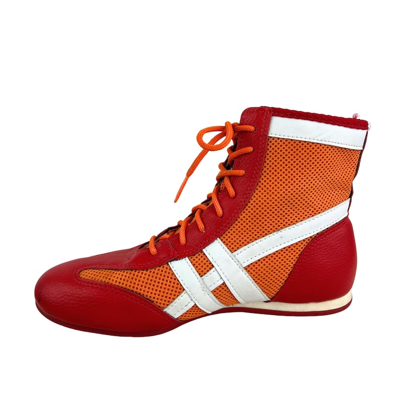 May include: Red and orange boxing shoes with white laces and a white mesh panel. The shoes have a white stripe across the toe and a white stripe across the side.