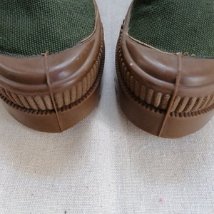 May include: A pair of dark green canvas shoes with brown rubber soles. The soles have a textured pattern.