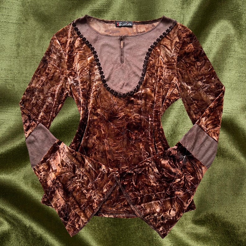 May include: A brown velvet long-sleeve top with a lace trim neckline and bell sleeves. The top has a crinkled texture and a brown underlay.