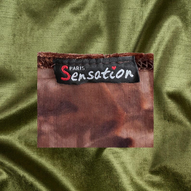 May include: A brown velvet clothing tag with the text "PARIS Sensation" in black with a small red heart.