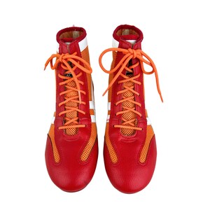 May include: A pair of red and orange boxing shoes with white laces. The shoes have a mesh panel on the side and a white stripe around the toe.