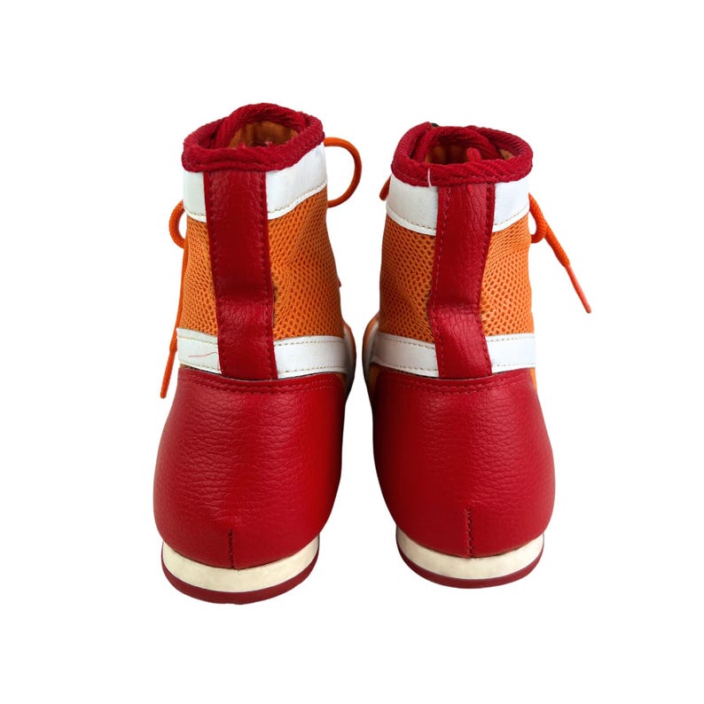 May include: A pair of red and orange boxing shoes with white accents. The shoes have a high top design and are laced up.