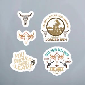 May include: Five white stickers with a western theme. The stickers feature a cow skull, a cowgirl riding a horse, a cow skull with a turquoise design, a cow skull with a turquoise design and two pistols, and a text sticker that says "You should probably leave".