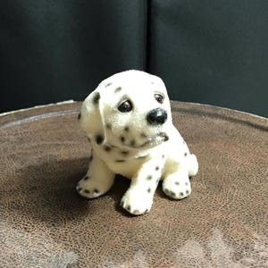 May include: A set of three ceramic mugs with a speckled, cream-colored glaze. Each mug features a different hand-painted design: a blue and green leaf, a yellow flower, and a red berry. The mugs have a simple, rounded shape and a comfortable handle.