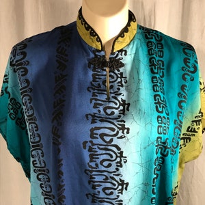 May include: A blue, green, and yellow patterned shirt with a mandarin collar and a black button closure. The shirt has a gradient design with black abstract patterns.