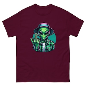 Könnte beinhalten: Ein maroonfarbenes T-Shirt mit einem grünen Außerirdischen, der ein kariertes Hemd und einen Hut trägt und den Mittelfinger zeigt.