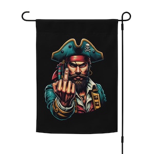 Puede incluir: Una bandera de jardín negra con una ilustración colorida de un pirata haciendo el dedo medio. El pirata lleva un sombrero azul y verde con una calavera y huesos cruzados.
