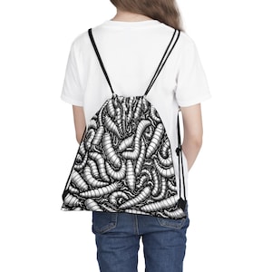 Puede incluir: Una mochila negra con cordón de ajuste con un patrón blanco de gusanos. La mochila la lleva puesta una persona.