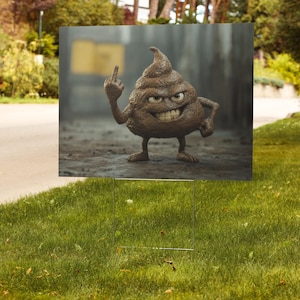 May include: A brown, cartoonish poop emoji with an angry expression and raised middle finger is featured on a yard sign. The sign is set on a green lawn with a metal frame. The background shows a blurred street and trees.