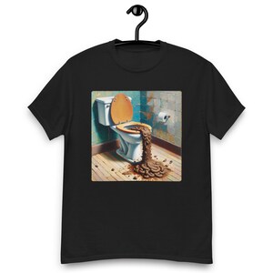 May include: Black t-shirt featuring a graphic of a toilet with the lid up, overflowing with brown material. The toilet is in a bathroom setting with a wooden floor and blue-green walls. A roll of toilet paper is on the wall.