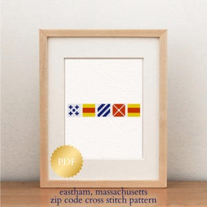 May include: A framed cross-stitch pattern featuring a series of colorful nautical signal flags. The flags are in blue, red, and yellow, set against a white background. The text "eastham, massachusetts zip code cross stitch pattern" is at the bottom.