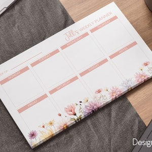 May include: A weekly planner with a floral design. The planner has spaces for each day of the week, as well as a notes section. The text "Jill's Weekly Planner" is at the top of the page.