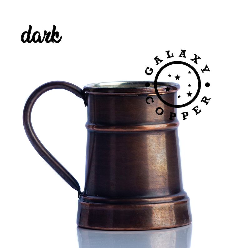 May include: A dark copper mug with a handle. The mug has a band around the middle and a wide base. The mug is sitting on a white surface. The text "GALAXY COPPER" is printed in a circle around the top of the mug.