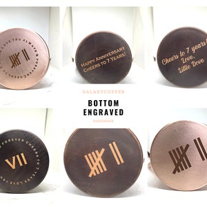May include: Six different copper mugs with engraved designs on the bottom. The designs include roman numerals, the words "Cheers to 7 years!" and "Love. Little Dove", and the words "7 Years Love You Always and Forever Cheers to".