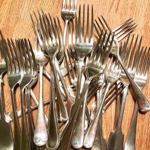 May include: A pile of silver forks with ornate handles. The forks are arranged in a random pattern, with some forks overlapping others.