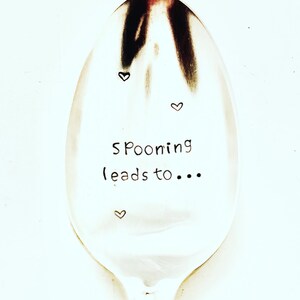 May include: A silver spoon with the text "Spooning leads to..." engraved on it. Three small hearts are also engraved on the spoon.