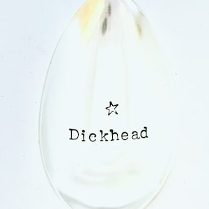 May include: A silver spoon with a star and the word "Dickhead" engraved on it.