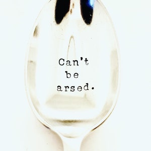 Puede incluir: Una cuchara de plata con el texto "Can't be arsed." grabado en la parte delantera.
