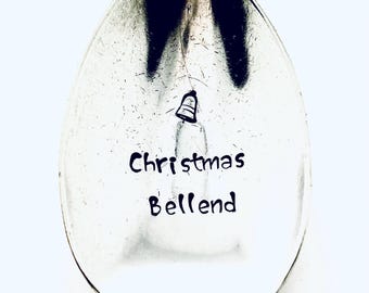 May include: A silver spoon with the words "Christmas Bellend" engraved on it. A small bell icon is above the text.