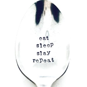 以下が含まれることがあります： 「eat sleep slay repeat」と刻まれた銀のスプーンです。