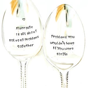 May include: Two silver spoons with engraved sayings. The first spoon says "Marriage is all about solving problems together". The second spoon says "Problems you wouldn't have if you were single".