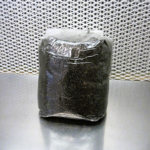 May include: A black bag of potting soil wrapped in clear plastic.