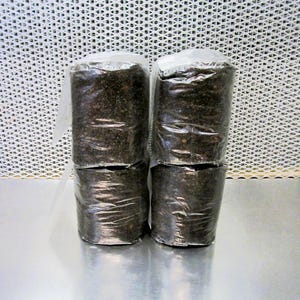 May include: Four packages of black soil, each wrapped in clear plastic, stacked in two pairs on a silver surface.