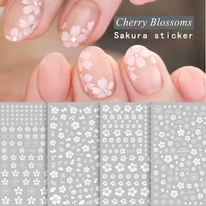 May include: Three sheets of white nail stickers with cherry blossom designs. The stickers are on a gray background. The stickers are labeled "F724", "F725", and "F726".