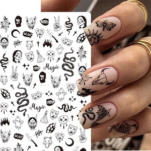 May include: Black and white nail art stickers with various designs including snakes, skulls, crosses, and the word "Magic".