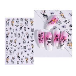 May include: Nail art stickers featuring abstract figures, flowers, and the phrases "GOOD LIVE", "BE AU TY", and "ADV ENT URE". The image also shows several manicured nails with floral and abstract designs, including the text "Stay WILD Moon CHID".