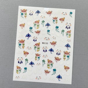 May include: A sheet of white nail stickers with a variety of colorful designs, including clouds, raindrops, and umbrellas. The stickers are perfect for adding a touch of whimsy to your nails. The sheet also includes the text "WG132".