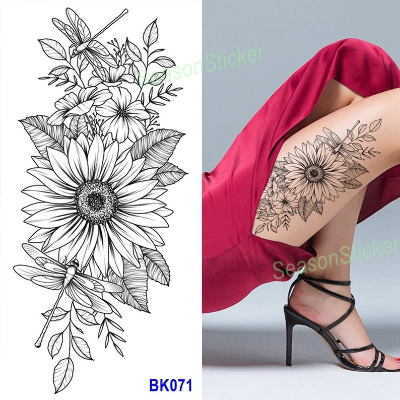 Pu&ograve; includere: Disegno di tatuaggio temporaneo in bianco e nero con un girasole con accenti di libellula. Il design del tatuaggio &egrave; mostrato sulla gamba di una persona.
