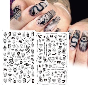 May include: Black and white nail art stickers with various designs, including skulls, snakes, hearts, eyes, and the words "Love", "Magic", and "F792".