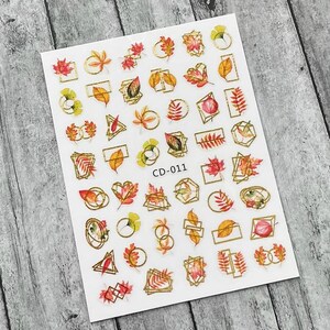 May include: A sheet of nail art stickers featuring autumn leaves in shades of red, orange, and yellow, accented with gold geometric frames. The stickers include various leaf designs and the text "CD-011".
