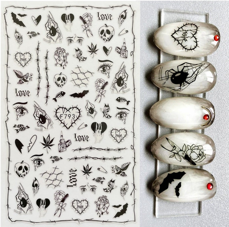 May include: A sheet of black and white nail art stickers with various designs, including hearts, bats, spiders, eyes, and the word "love".