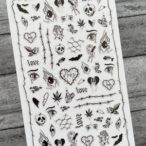 May include: A sheet of black and white stickers featuring various gothic and grunge-inspired designs. The stickers include hearts, eyes, spiders, bats, flowers, and more. The text "Love" and "Hate" appears on some of the stickers.  F793 is also printed on one of the stickers.