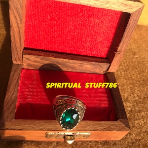 Könnte beinhalten: Ein silberner Ring mit einem großen grünen Edelstein, der in eine dekorative Silberfassung gefasst ist. Der Ring befindet sich in einer kleinen Holzkiste mit rotem Samtbezug. Der Text "SPIRITUAL STUFF786" ist auf der Kiste sichtbar.
