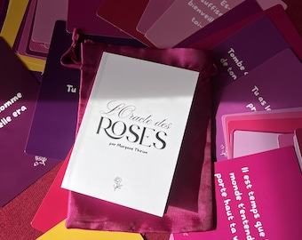 Peut inclure: Un jeu de cartes oracle dans des tons de rose, violet et jaune, avec du texte en français sur chaque carte. Un livret blanc intitulé L'Oracle des ROSES par Morgane Thirion repose sur une pochette en satin rose foncé.
