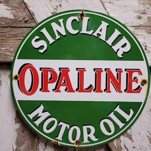 May include: A vintage, round, metal sign with a green background and white lettering. The sign reads "Sinclair Opaline Motor Oil". The text "Opaline" is in red.